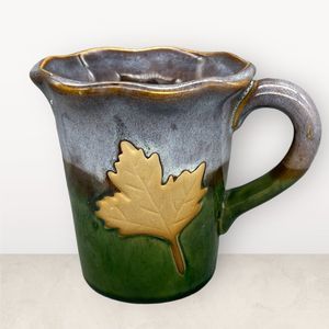 Handmade unmarked Pottery Mug with Maple Leaf and Blue and Green Drip Glaze